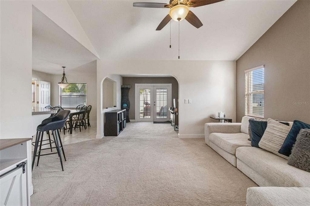 A living room with beige carpet, a vaulted ceiling, and an arched opening to a dining area — 4181 CENTER POINTE CIRCLE UNIT 91B, SARASOTA, FL
