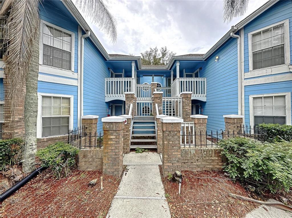 A blue two-story apartment building with brick pillars and a central staircase — 2717 N POINCIANA BLVD UNIT 173, KISSIMMEE, FL