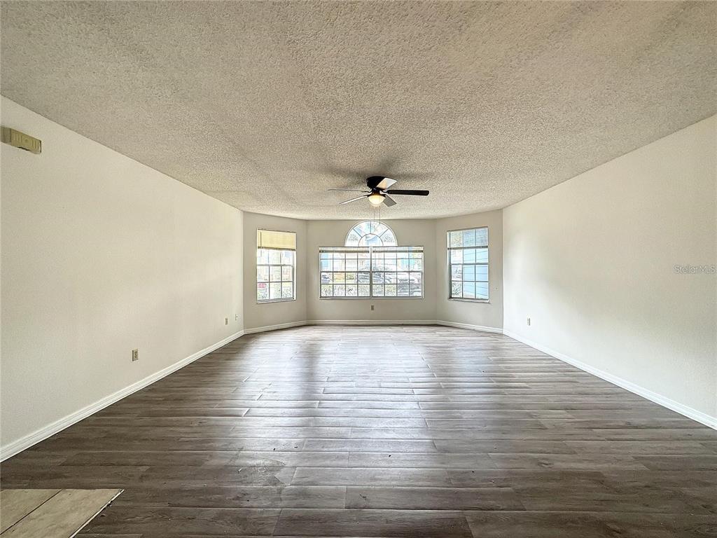 An empty living room features wood-look flooring, white walls, and a ceiling fan — 2717 N POINCIANA BLVD UNIT 173, KISSIMMEE, FL