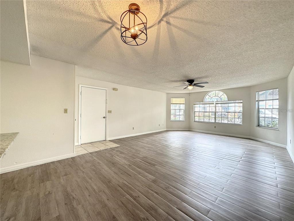 A living room with light wood-look flooring, a ceiling fan, and a geometric pendant light — 2717 N POINCIANA BLVD UNIT 173, KISSIMMEE, FL