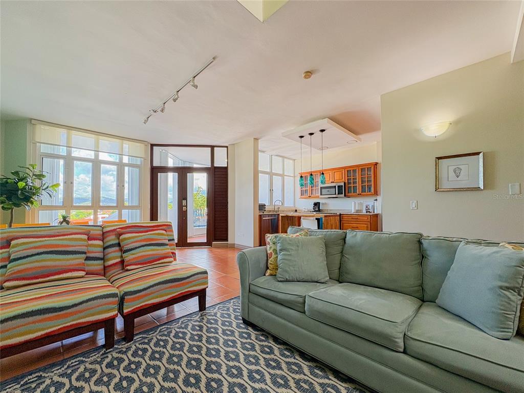 A living room features a striped sofa, a light green sofa, and an open kitchen — 6000 RIO MAR BLVD VILLA LAS BRISAS UNIT 10A, RIO GRANDE, PR
