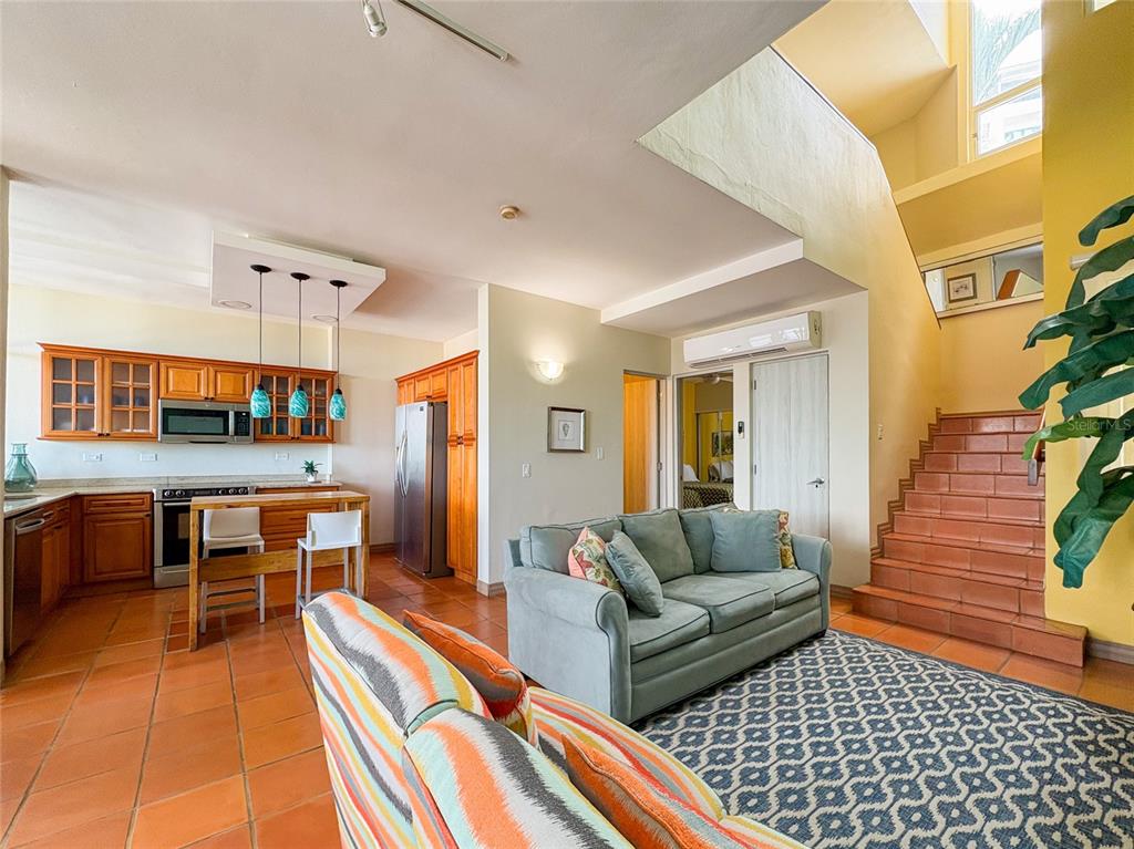 An open-concept living room and kitchen featuring tile floors, wood cabinetry, and a staircase — 6000 RIO MAR BLVD VILLA LAS BRISAS UNIT 10A, RIO GRANDE, PR