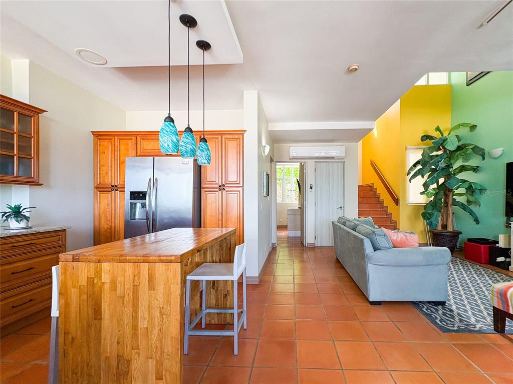 A kitchen with wood cabinets and an island opens into a living area with tile floors — 6000 RIO MAR BLVD VILLA LAS BRISAS UNIT 10A, RIO GRANDE, PR
