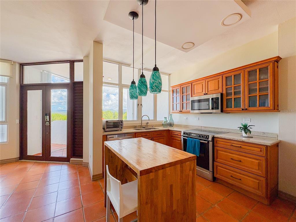 A kitchen features wood cabinets, a wooden island, pendant lights, and tile flooring — 6000 RIO MAR BLVD VILLA LAS BRISAS UNIT 10A, RIO GRANDE, PR