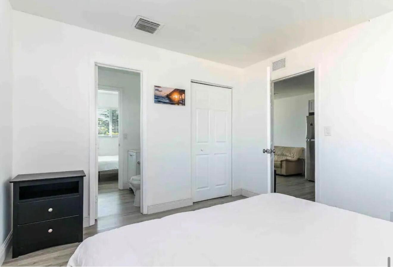 A bedroom with white walls, a black nightstand, a bed, and two doorways — 2499 NE 2nd Avenue # B, Boca Raton FL 33431, BOCA RATON, FL