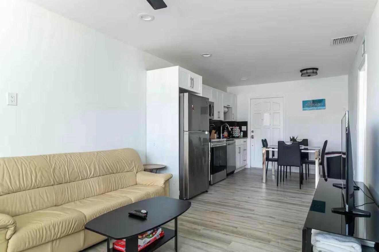 An open-concept living area features a beige sofa, a kitchen with stainless appliances, and dining — 2499 NE 2nd Avenue # B, Boca Raton FL 33431, BOCA RATON, FL