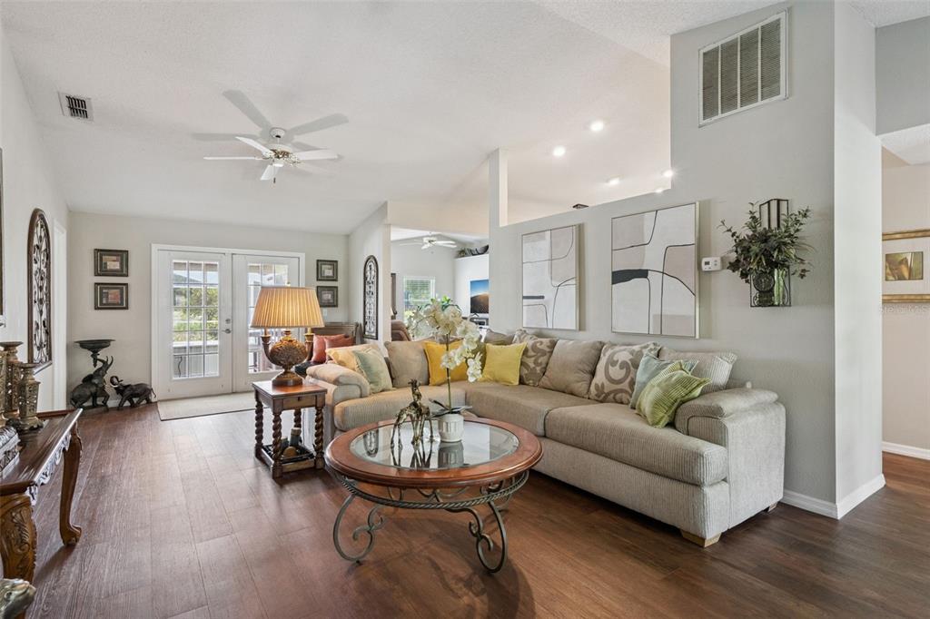 A living room features a sectional sofa, a glass-topped coffee table, and wood-look flooring — 3339 SLASH PINE DRIVE, LAKE WALES, FL