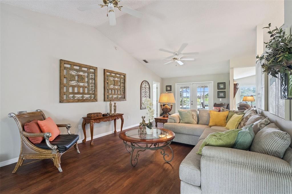 A living room features wood flooring, a vaulted ceiling, a sectional sofa, and a rattan chair — 3339 SLASH PINE DRIVE, LAKE WALES, FL