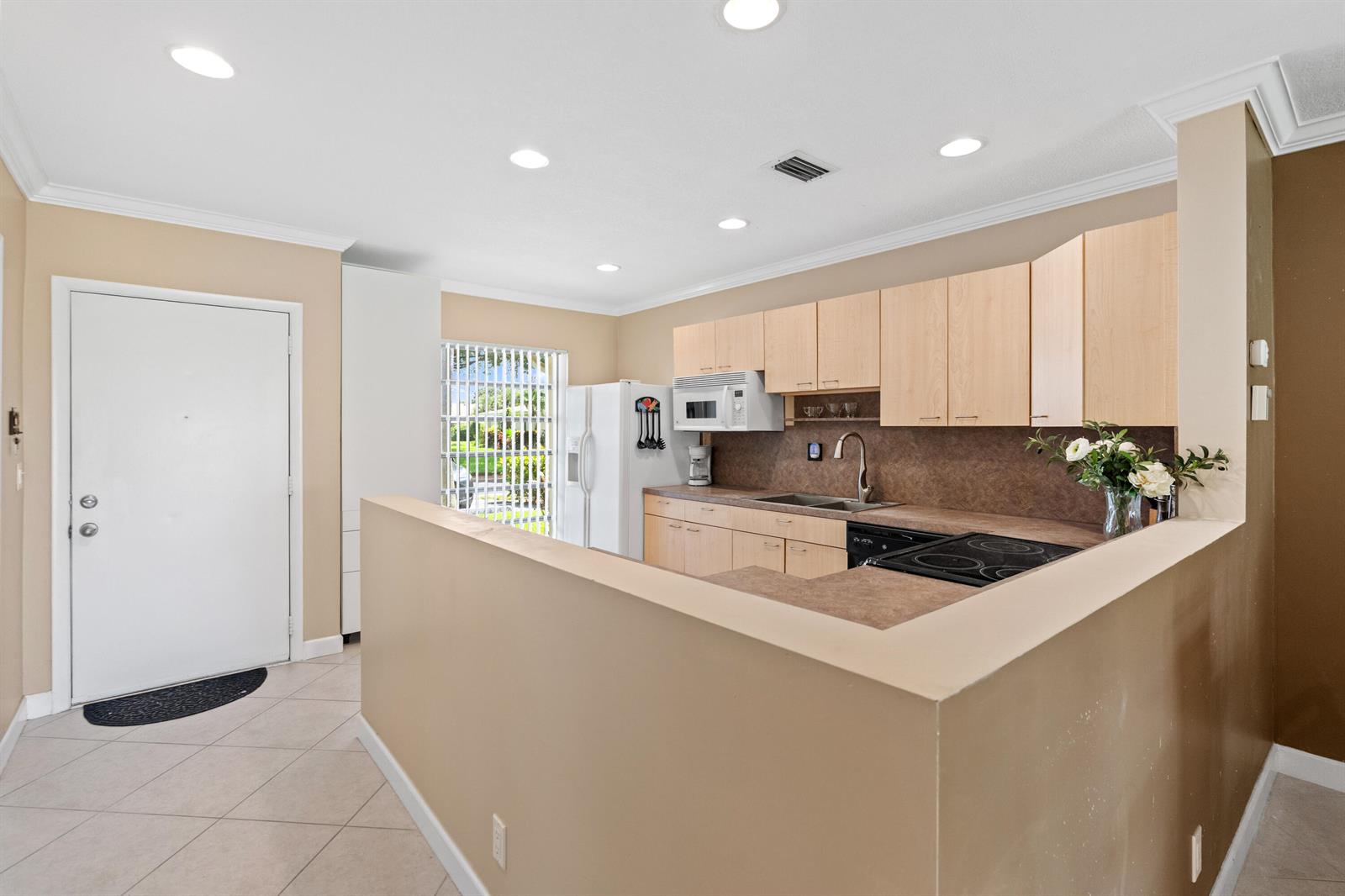 A kitchen features light wood cabinets, a brown countertop, and a white refrigerator — 8666 Bella Vista Drive # 111, Boca Raton FL 33433, BOCA RATON, FL