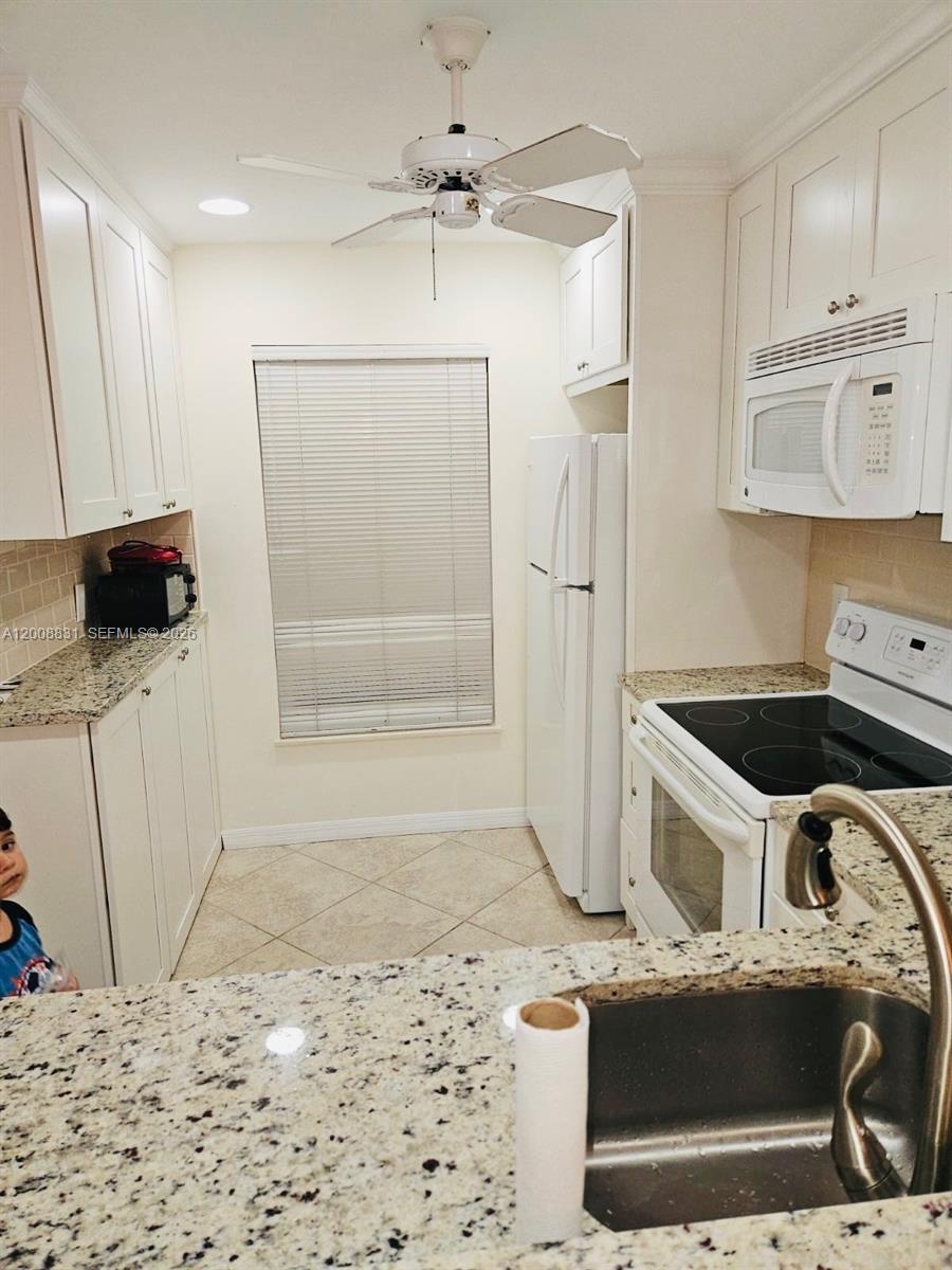 A kitchen features white cabinets, granite countertops, a white refrigerator, and a ceiling fan — 1335 Mainsail Dr # 1315, Naples FL 34114, NAPLES, FL