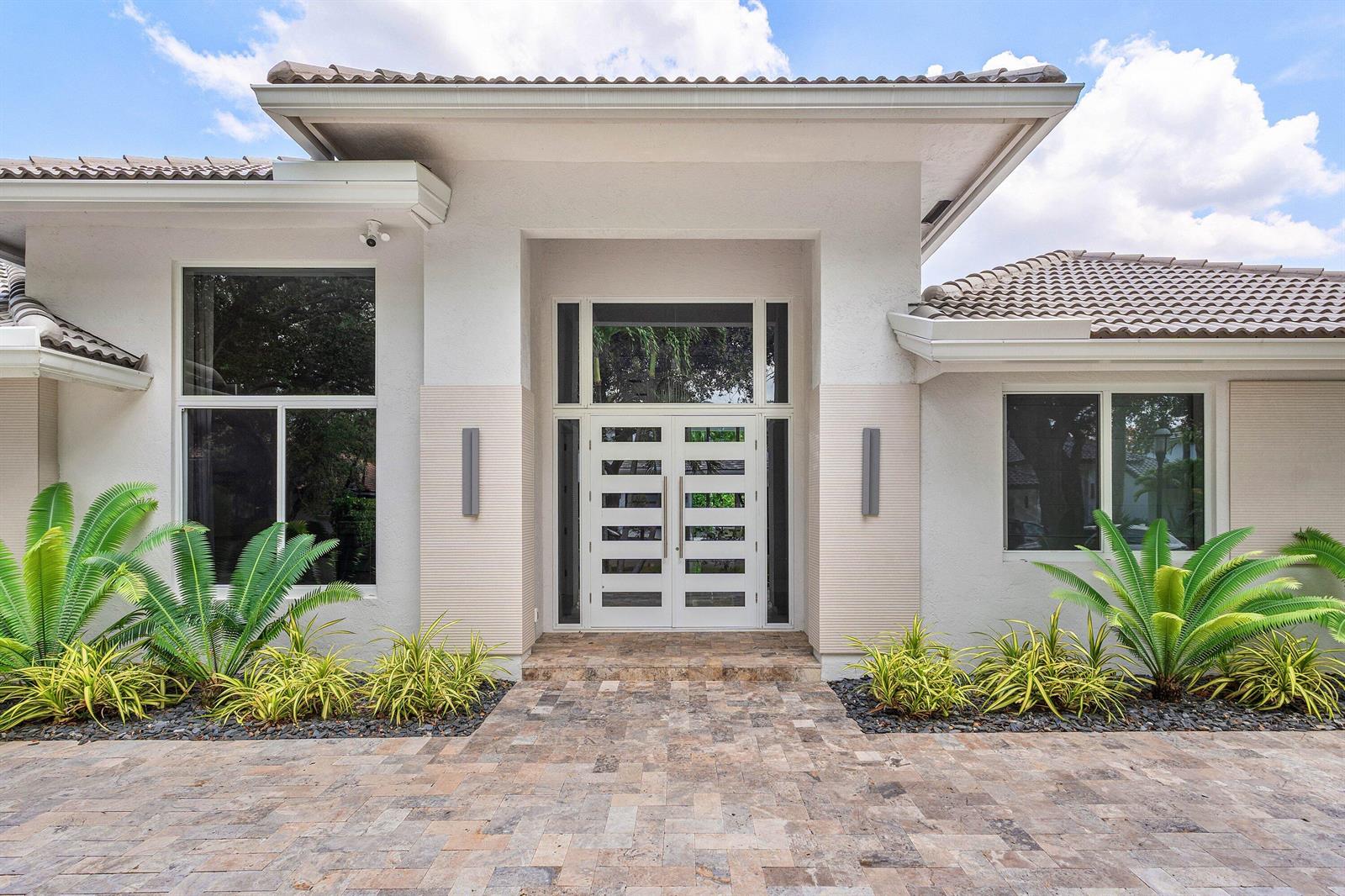 The exterior of a modern home features a double front door and stone paver walkway — 3164 Saint Annes Drive, Boca Raton FL 33496, BOCA RATON, FL