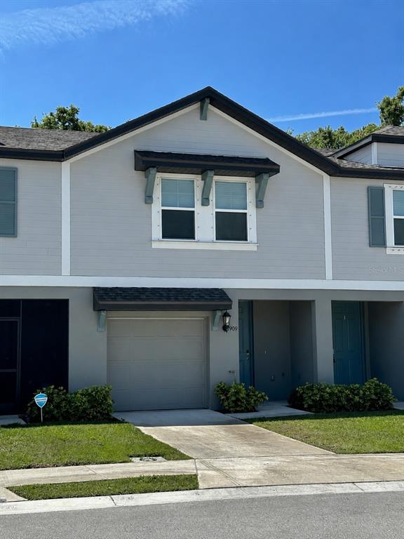 A two-story townhouse exterior features a single-car garage, light gray siding, and a blue door — 5909 SAILOR COAST WAY, NOKOMIS, FL