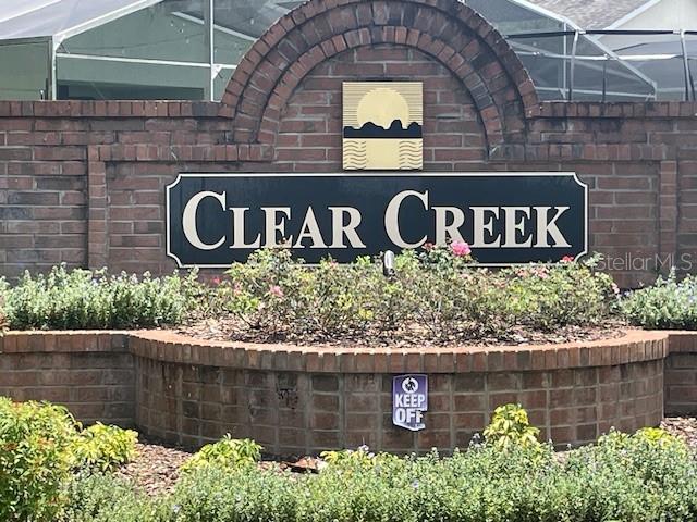A brick sign for Clear Creek stands in front of a landscaped garden bed — 1048 WINDING WATER WAY, CLERMONT, FL