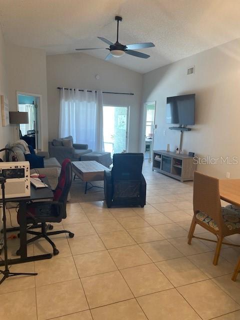 A living room with tile floors, a ceiling fan, a television, and a dining area — 1048 WINDING WATER WAY, CLERMONT, FL