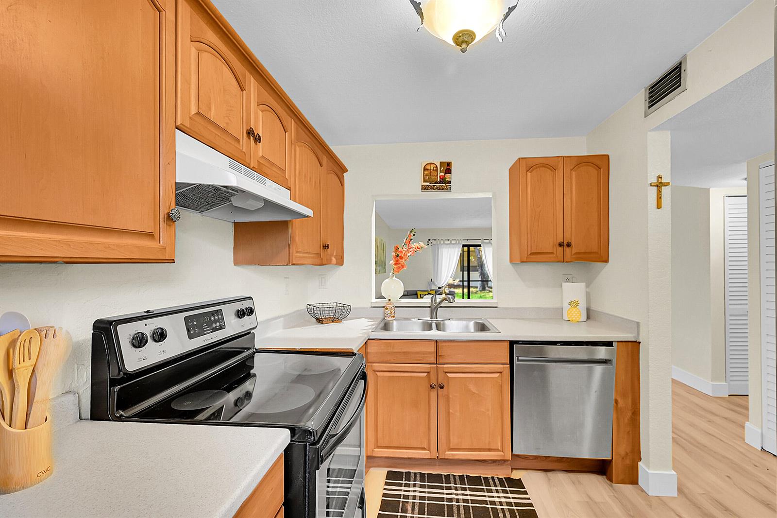 A kitchen features wood cabinets, stainless steel appliances, a double sink, and a pass-through window — 9503 Boca Cove Circle # 603, Boca Raton FL 33428, BOCA RATON, FL