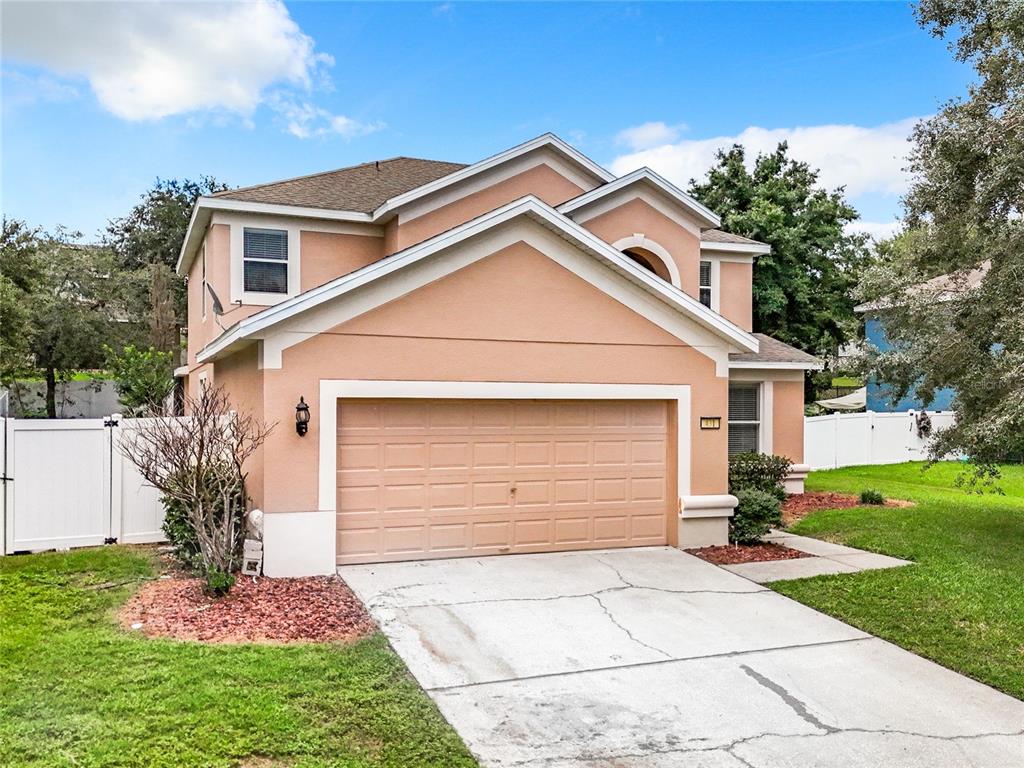 A two-story peach-colored house with a two-car garage and a concrete driveway — 431 BALBOA BOULEVARD, CLERMONT, FL