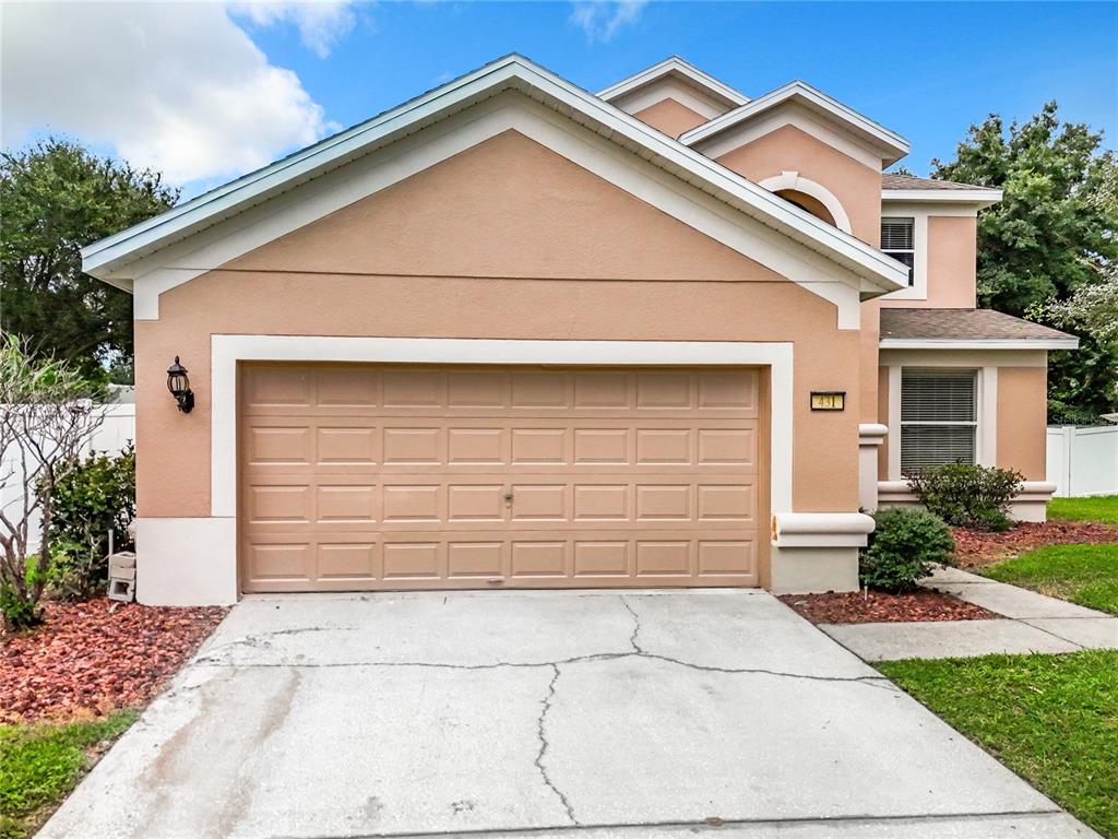 A peach-colored house with a two-car garage and a cracked concrete driveway — 431 BALBOA BOULEVARD, CLERMONT, FL