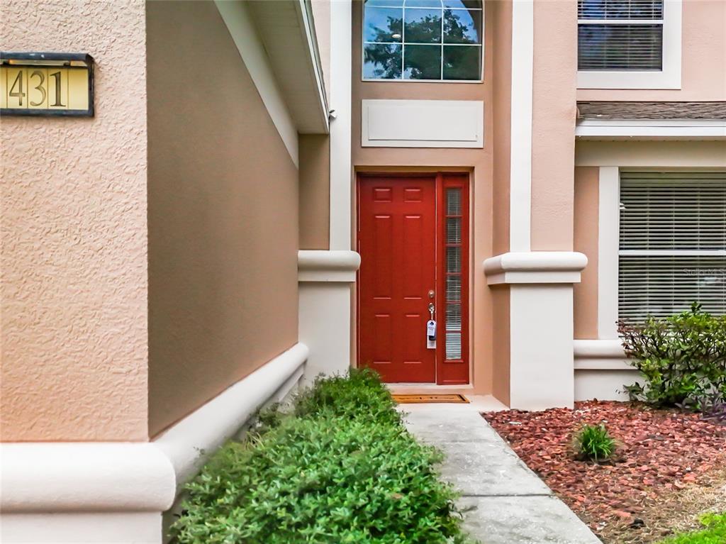 A red front door is framed by white pillars and a small walkway — 431 BALBOA BOULEVARD, CLERMONT, FL