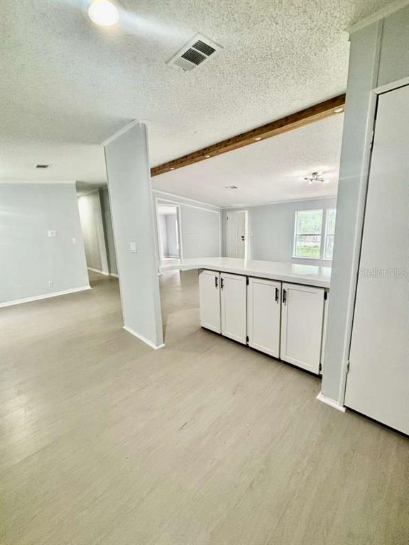 A kitchen island with white cabinets sits in an open-concept room with light wood flooring — 218 DIAMOND ACRES ROAD, DAVENPORT, FL