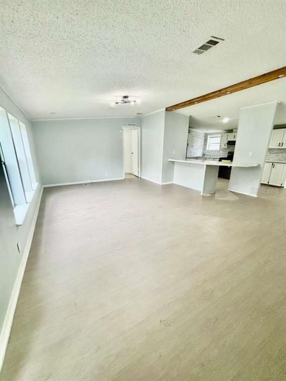 An open-concept living area features light-colored flooring, a kitchen island, and a doorway — 218 DIAMOND ACRES ROAD, DAVENPORT, FL