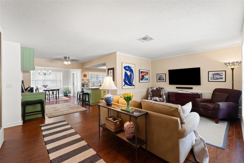 A living room with hardwood floors, a beige sofa, and an open kitchen with green cabinets — 8802 SEELEY LANE, HUDSON, FL