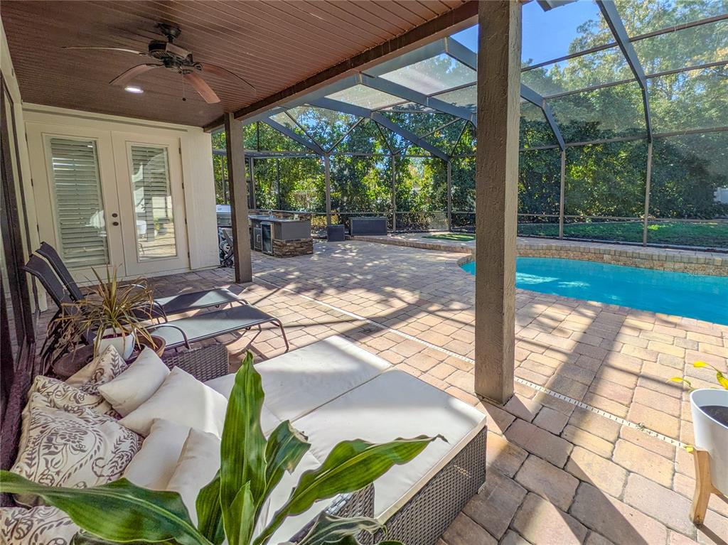 A covered patio features a pool, outdoor kitchen, and lounge furniture inside a screened enclosure — 2512 TUSCAN OAKS LANE, JACKSONVILLE, FL