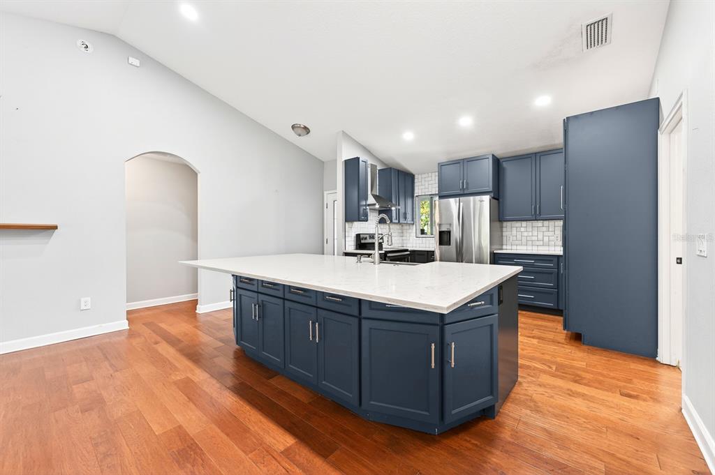 A kitchen features a large blue island with a white countertop and hardwood flooring — 116 W 5TH STREET, CHULUOTA, FL