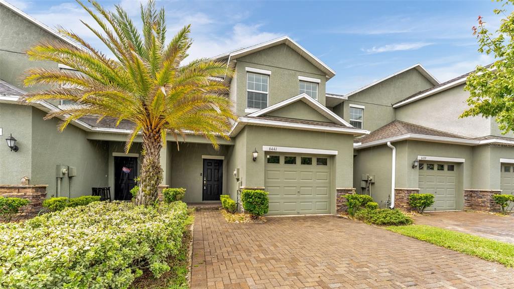 A two-story townhouse with a paved driveway, a garage, and a palm tree in front — 6441 TORRINGTON CIRCLE, LAKELAND, FL