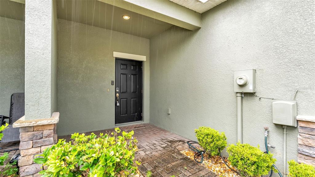 A covered entryway features a black front door, stone pillar, and paved walkway — 6441 TORRINGTON CIRCLE, LAKELAND, FL