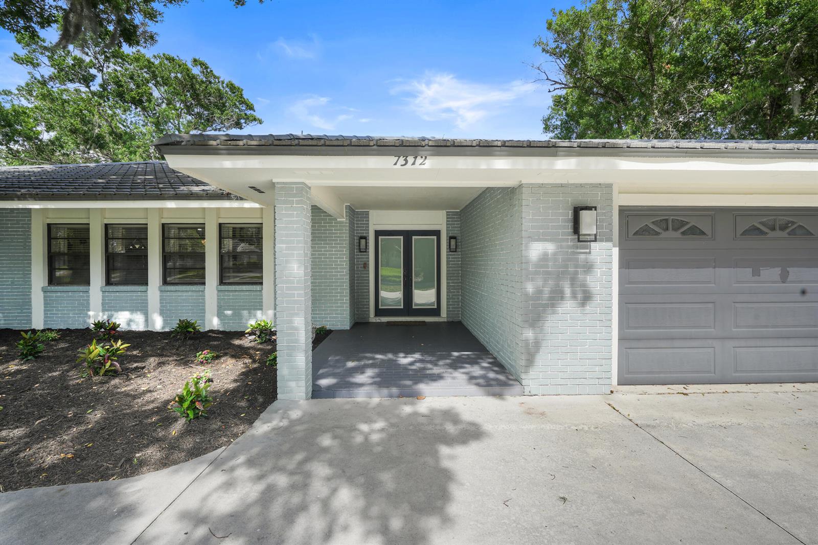 The exterior of a single-story house features light blue brick, a gray garage door, and a covered entryway — 7312 Elyse Circle, Port St. Lucie FL 34952, PORT ST. LUCIE, FL