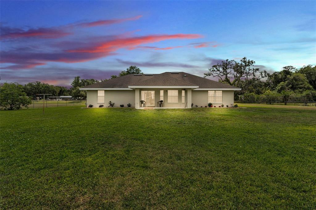 A wide-angle exterior view of the back of a single-story house with a large lawn — 8904 CARROLWOOD DRIVE, LAKELAND, FL