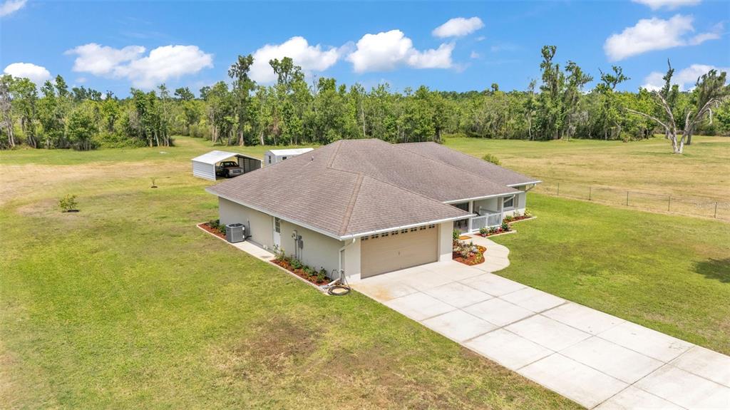 An aerial view shows a single-story house with a tan exterior, hip roof, and driveway — 8904 CARROLWOOD DRIVE, LAKELAND, FL