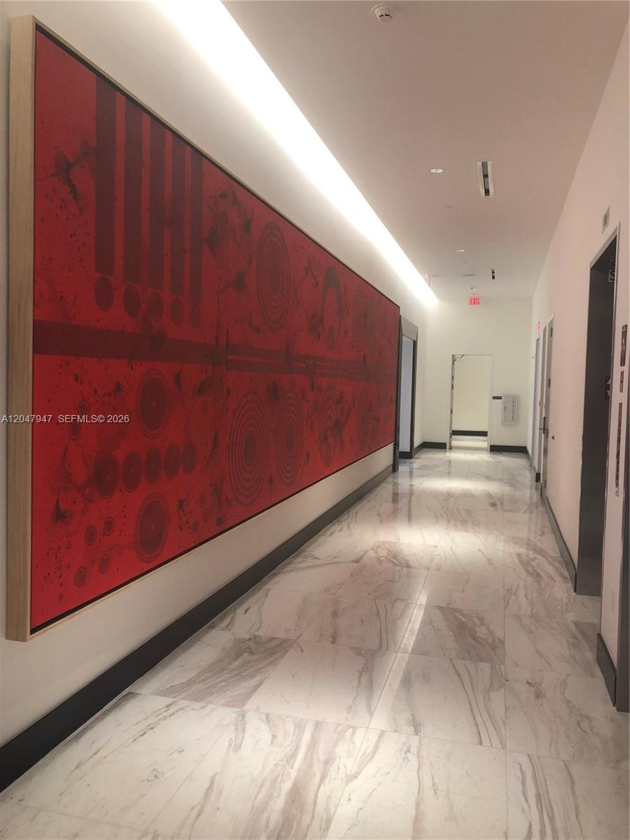 A long hallway features a large red abstract painting on the wall and marble flooring — 851 NE 1st Ave # 3705, Miami FL 33132, MIAMI, FL