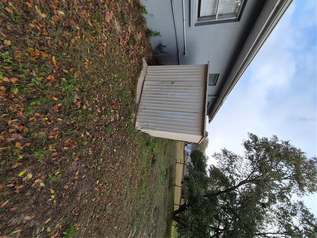 A metal storage shed sits on the grass next to the side of a house — 11 S BARBOUR STREET, BEVERLY HILLS, FL