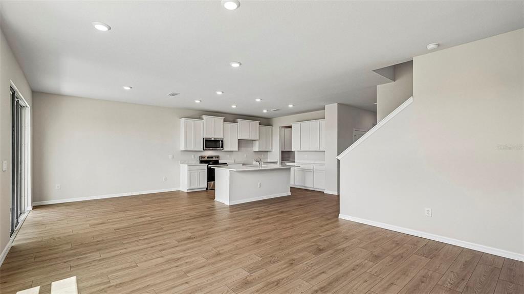 An open-concept kitchen with white cabinets, a central island, and wood-look flooring — 2818 FISHERY COURT, LAKEWOOD RANCH, FL
