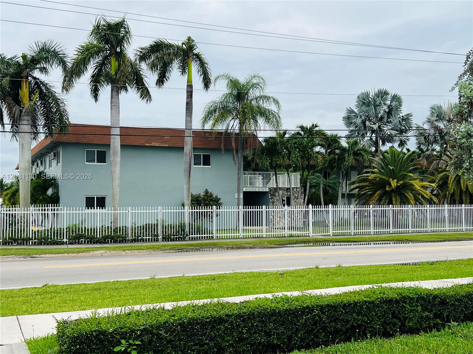A two-story apartment building with a white fence and palm trees sits along a road — 880 NE 18th Ave # 3, Homestead FL 33033, HOMESTEAD, FL