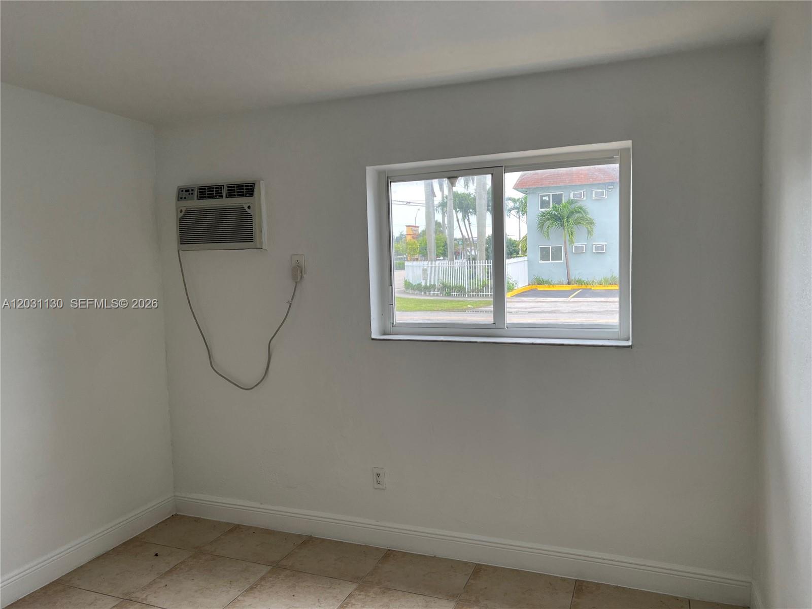 A room with white walls, tile flooring, a window air conditioner, and a sliding window — 880 NE 18th Ave # 3, Homestead FL 33033, HOMESTEAD, FL
