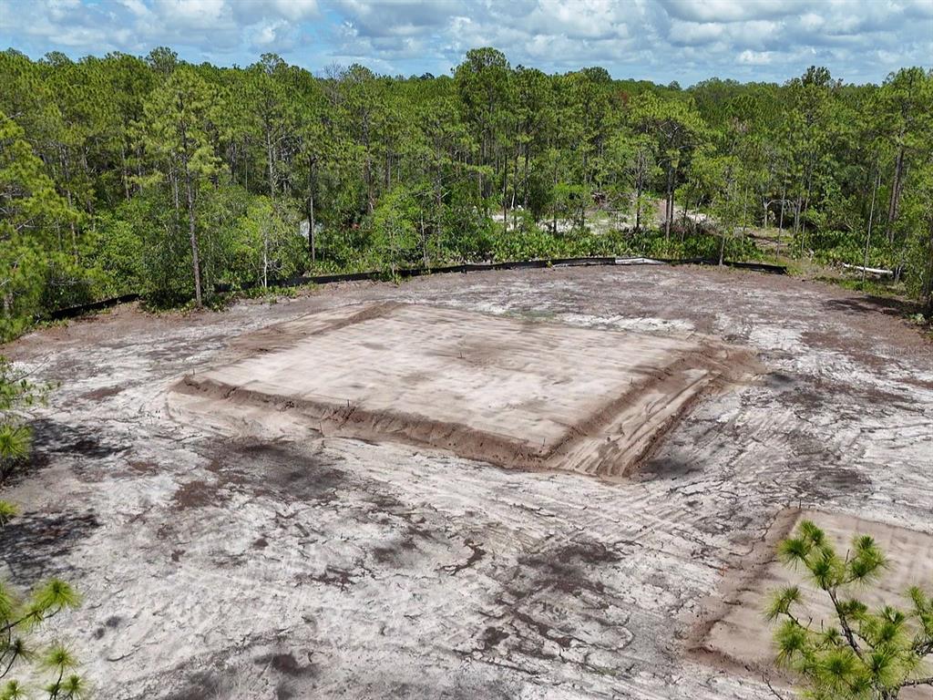 An aerial view shows a cleared residential lot with a prepared building pad and foundation — 4678 GUM ROAD, NEW SMYRNA BEACH, FL