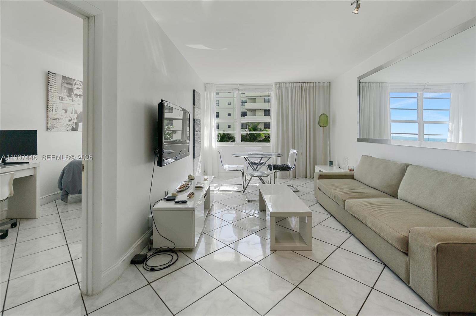 A living room features white tile floors, a beige sofa, and a glass dining set — 100 Lincoln Rd # 638, Miami Beach FL 33139, MIAMI BEACH, FL