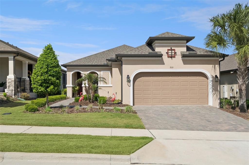 A single-story beige house with a two-car garage, arched entryway, and a paved driveway — 959 BRAEWOOD DRIVE, CLERMONT, FL