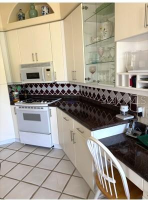 A kitchen features white cabinets, a microwave, a stove, and a dark countertop — 8974 GREY OAKS AVENUE, SARASOTA, FL