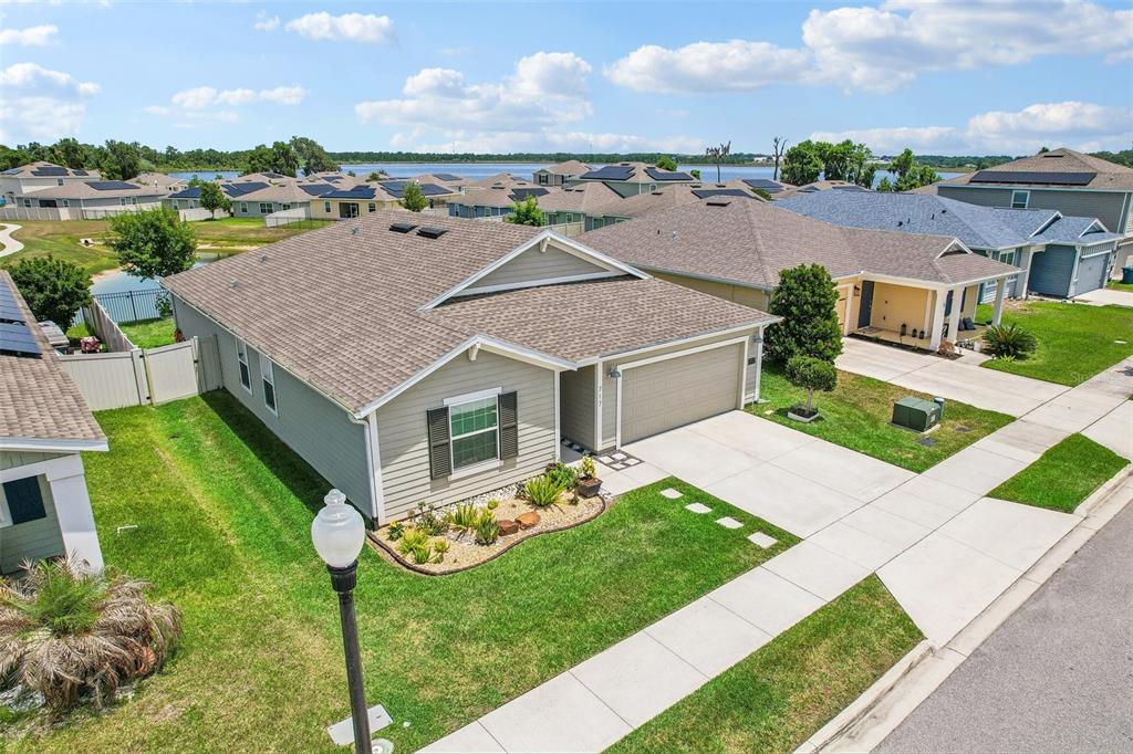 An aerial view shows a single-story suburban house with a tan exterior and gray roof — 717 SIMONE COURT, HAINES CITY, FL