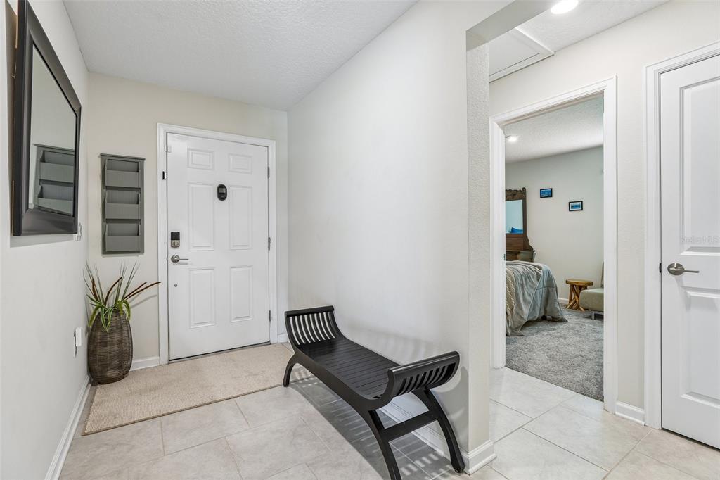 A bright entryway features a white front door, a black bench, and tiled flooring — 717 SIMONE COURT, HAINES CITY, FL