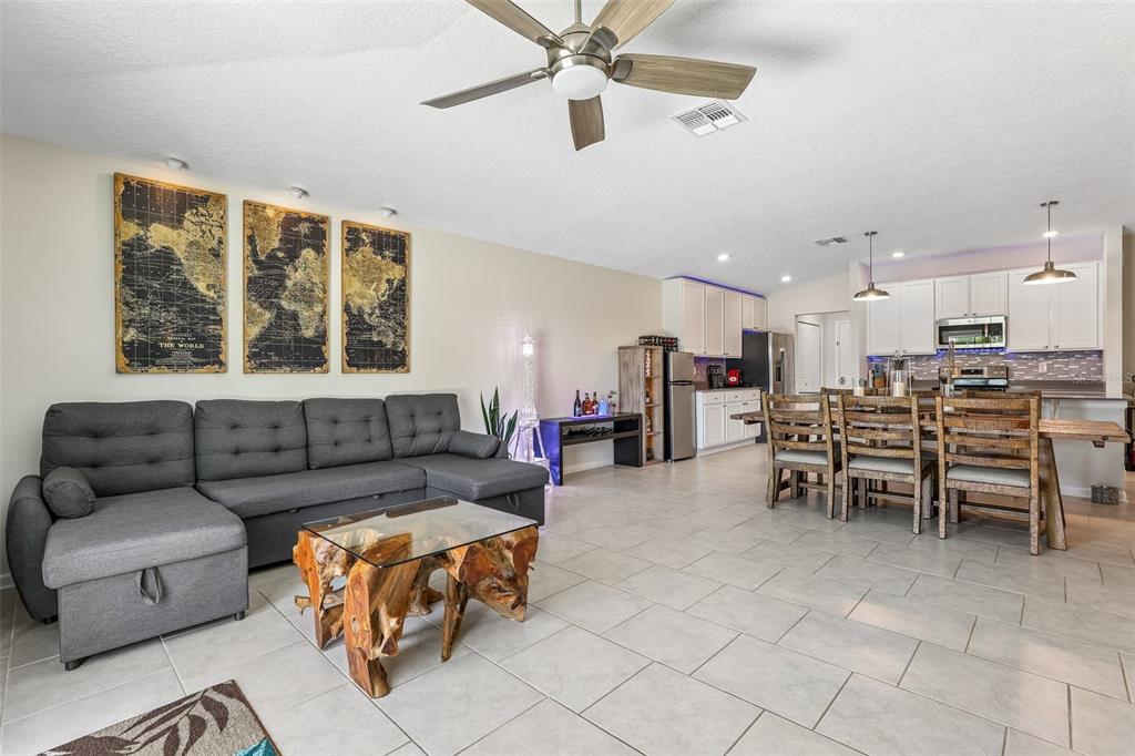A living room and dining area with a grey sectional, wood coffee table, and kitchen — 717 SIMONE COURT, HAINES CITY, FL