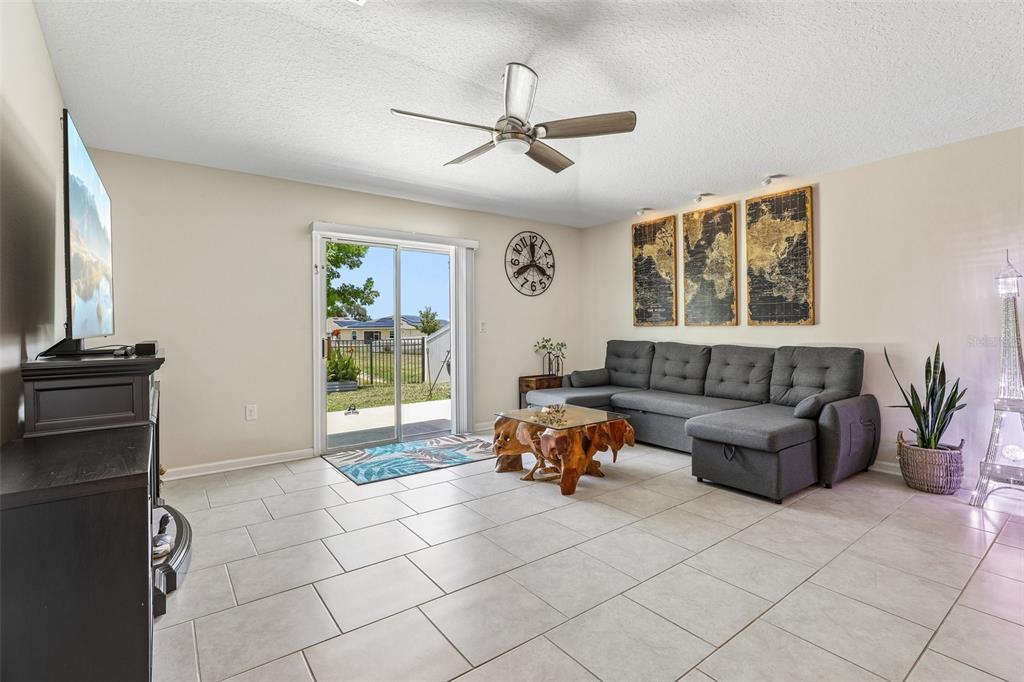 A living room features light tile flooring, a gray sectional sofa, and a sliding glass door — 717 SIMONE COURT, HAINES CITY, FL