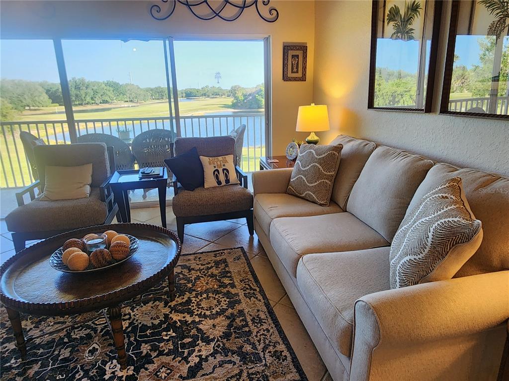 A living room features a sofa, two armchairs, a round coffee table, and a balcony view — 7224 CEDAR HOLLOW CIRCLE, BRADENTON, FL