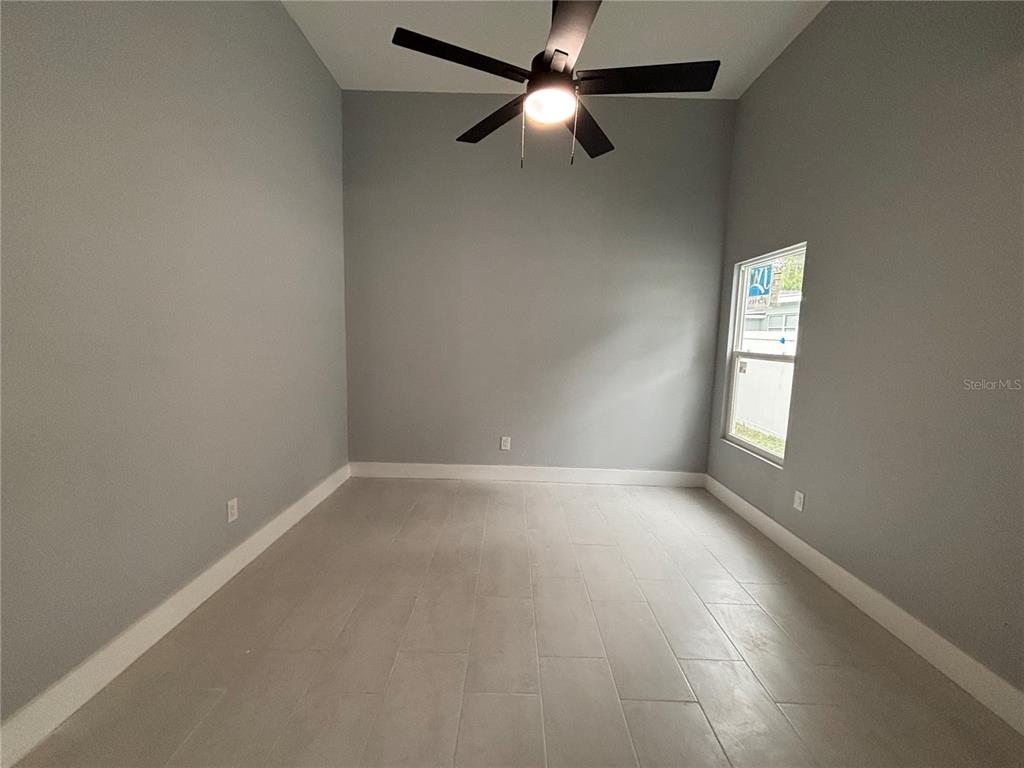 An empty room with gray walls, light tile flooring, and a ceiling fan — 2818 HARGILL DRIVE, ORLANDO, FL
