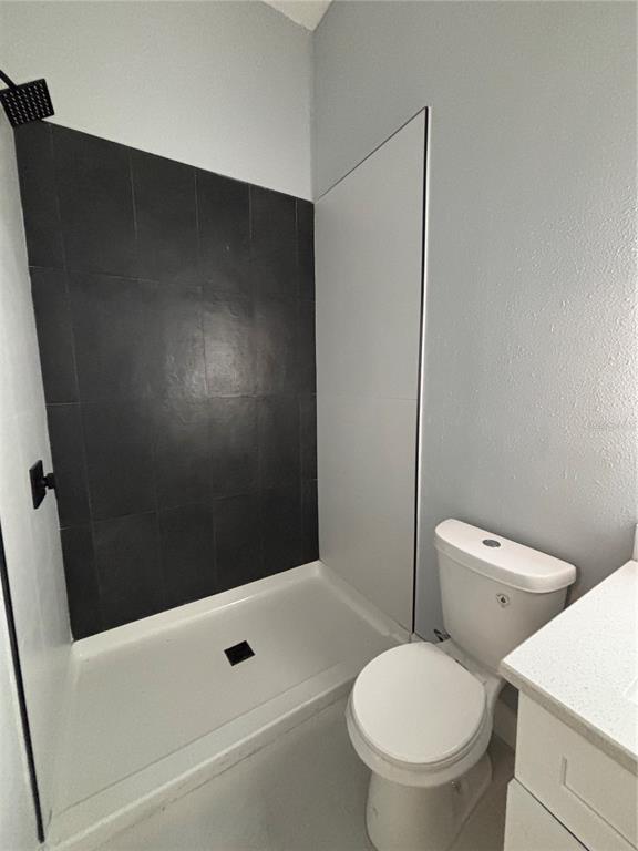 A bathroom features a walk-in shower with black tile, a white toilet, and a vanity — 2818 HARGILL DRIVE, ORLANDO, FL