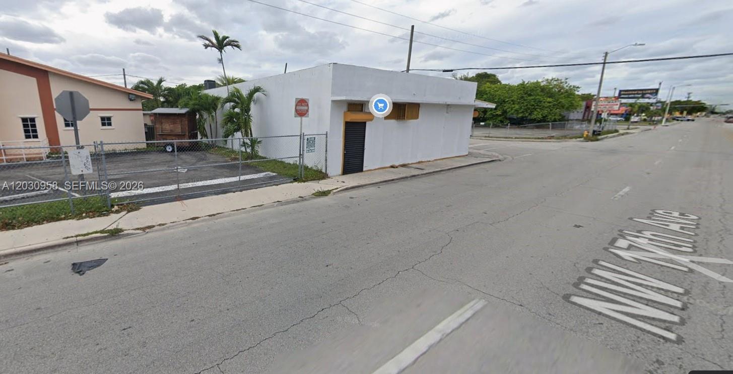 A white, single-story commercial building sits on a corner lot next to a fenced parking area — 5180 NW 17th Ave, Miami FL 33142, MIAMI, FL