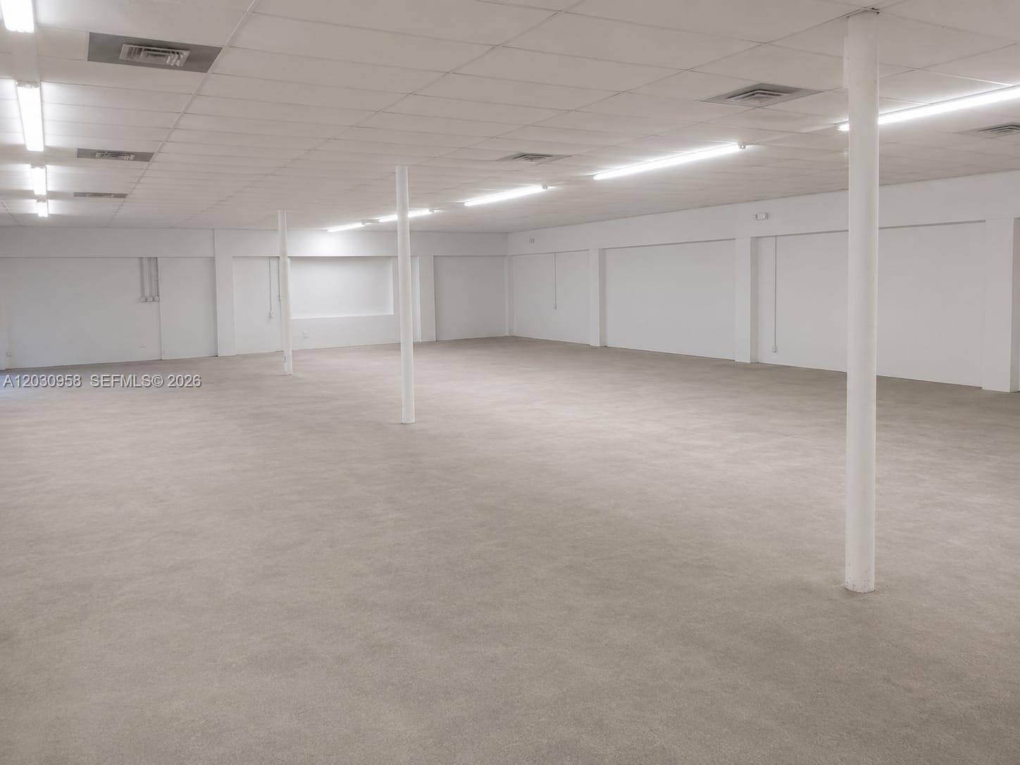 An empty, open-plan commercial space features white walls, a drop ceiling, and concrete flooring — 5180 NW 17th Ave, Miami FL 33142, MIAMI, FL